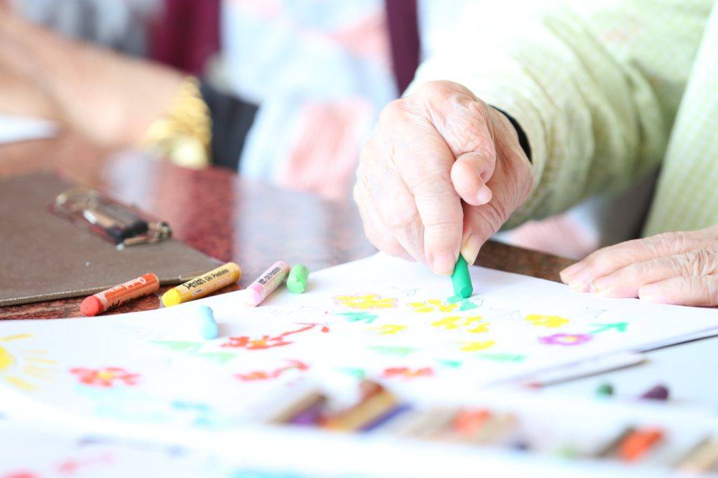 person hold a green pastel and drawing on a piece of paper